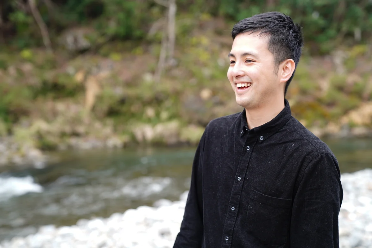 川辺で笑顔を見せる前田大介